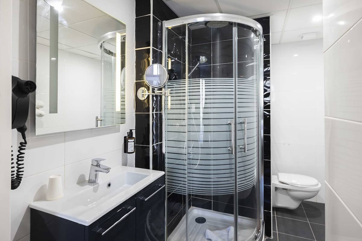 A modern bathroom with a glass-enclosed shower, a white sink, and a toilet.