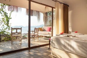 A bedroom with a bed, a chair, and a view of the sea. - Zakros Hotel Lykia (Fethiye)