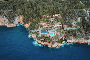 An aerial view of a coastal property with a swimming pool, surrounded by dense forest and rocky cliffs. - Zakros Hotel Lykia (Fethiye)