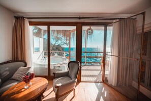 A room with a view of the sea, a sofa, a chair, and a table with a vase. - Zakros Hotel Lykia (Fethiye)