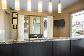 A reception area with a marble counter, a computer, framed certificates, and a TV mounted on the wall. - Econo Lodge Vernon Area (Vernon)