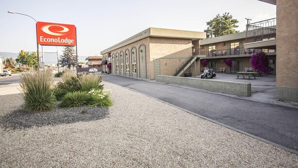 A building with a sign reading 'EconoLodge,' a parking area, and a staircase leading to a balcony with outdoor seating. - Econo Lodge Vernon Area (Vernon)