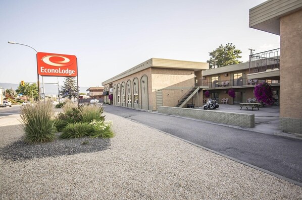 A building with a sign reading 'EconoLodge,' a parking area, and a staircase leading to a balcony with outdoor seating.