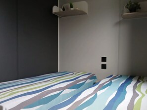 Ein Schlafzimmer mit einem Bett, einem Wandregal und einem Lichtschalter.