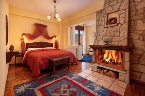 A cozy bedroom with a fireplace, a bed with a red bedspread, and a view of the outdoors. - Fretzato Guest House (Pyli)