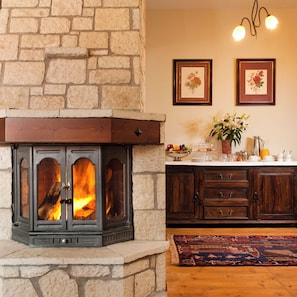 A stone fireplace with a fire, wooden cabinets, and a rug on the floor.