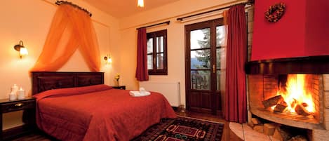 Un dormitorio con una cama grande, una chimenea, una ventana con cortinas y una lámpara fijada a la pared.