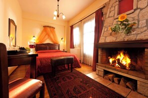 A cozy room with a bed, a fireplace, a desk with a lamp, and a window with curtains.