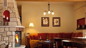 Un accogliente soggiorno con camino in pietra, un divano, un tavolino da caffè e un lampadario.