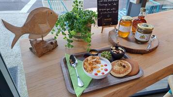 A wooden table with a fish decoration, a potted plant, a sign, jars of honey, and a plate with food.