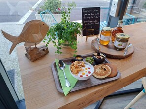 Ett träbord med en fiskformad dekoration, en krukväxt, en skylt, burkar med honung och en tallrik med mat.