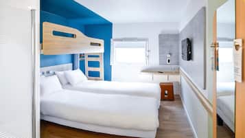 Quarto compacto com beliche, uma escrivaninha pequena e um espelho.