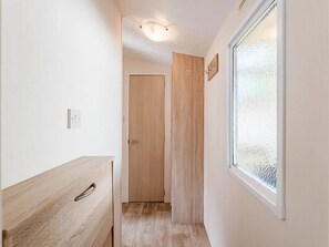 Ein Korridor mit einer Holztür, einem Fenster mit Milchglas und einem Lichtschalter an der Wand.