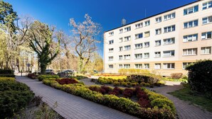 Un edificio con varias ventanas y un sendero pavimentado flanqueado por arbustos podados.