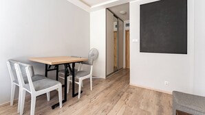 Una habitación con una mesa de madera y dos sillas, una pizarra en la pared y una puerta que da a otra habitación.