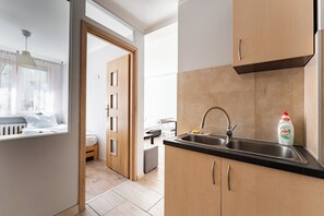 Eine moderne Küche mit Spüle, Holzschränken und Blick in ein Schlafzimmer.