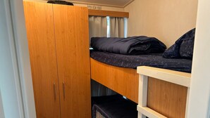 Ein Etagenbett mit einem Holzschrank und einer kleinen Regalwand.