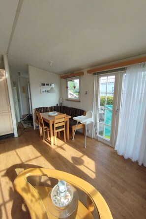 Une pièce spacieuse avec une table à manger en bois, une chaise blanche et une table basse avec un plateau en verre.