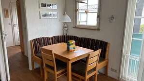 Ein Essbereich mit einem Holztisch und einer Bank, einer Hängelampe und gerahmten Bildern an der Wand.