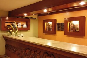 Una reception con piano in marmo, opere d'arte appese alla parete e un vaso con fiori.