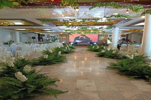 A spacious hall with a central aisle, white tablecloths, and green foliage. - The VIP Hotel by Zuzu (Cagayan de Oro)