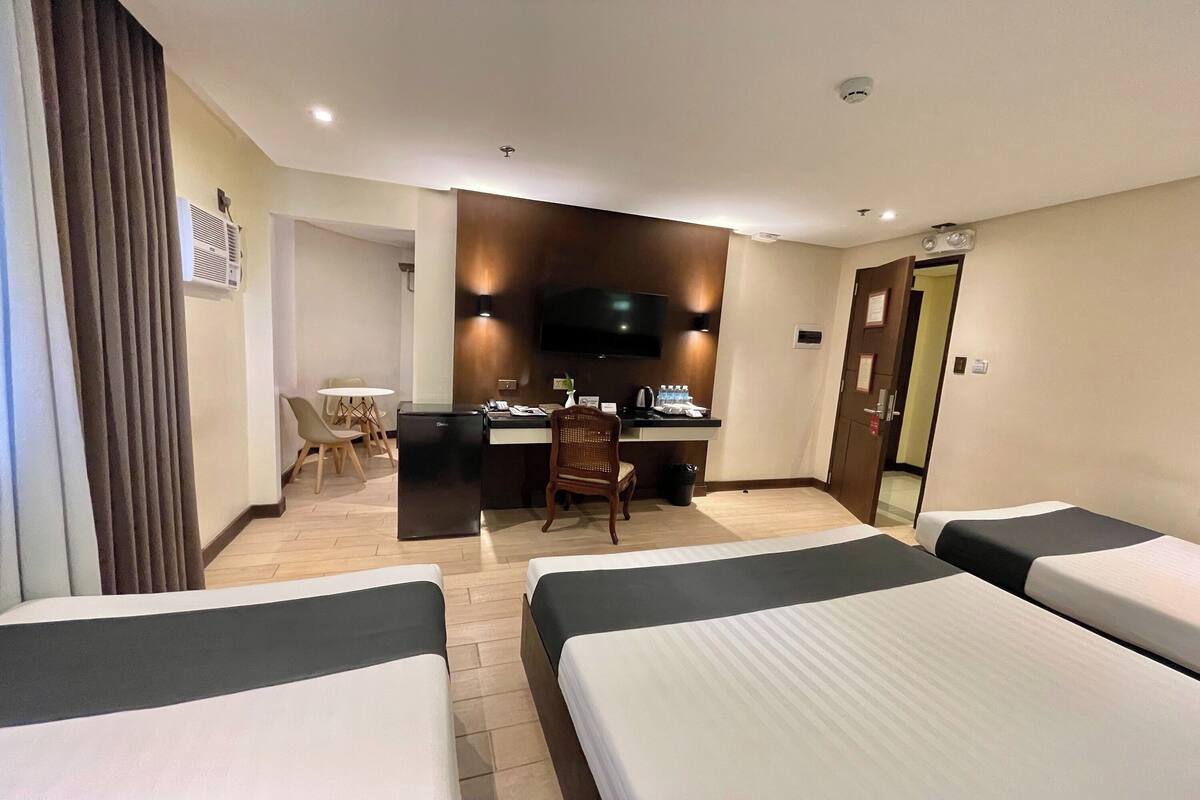 Hotellihuone, jossa on kaksi sänkyä, työpöytä, tuoli, televisio ja ovi.