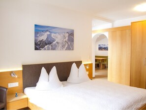 A hotel room with a bed, a nightstand, a wooden wardrobe, and a painting of a mountain landscape. - Apart Prieth Samnaun, (Samnaun-Ravaisch) by Interhome (Samnaun)