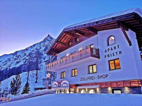 A hotel with a mountain backdrop, named 'Zollfrei-Shop,' featuring a balcony and multiple windows. - Apart Prieth Samnaun, (Samnaun-Ravaisch) by Interhome (Samnaun)