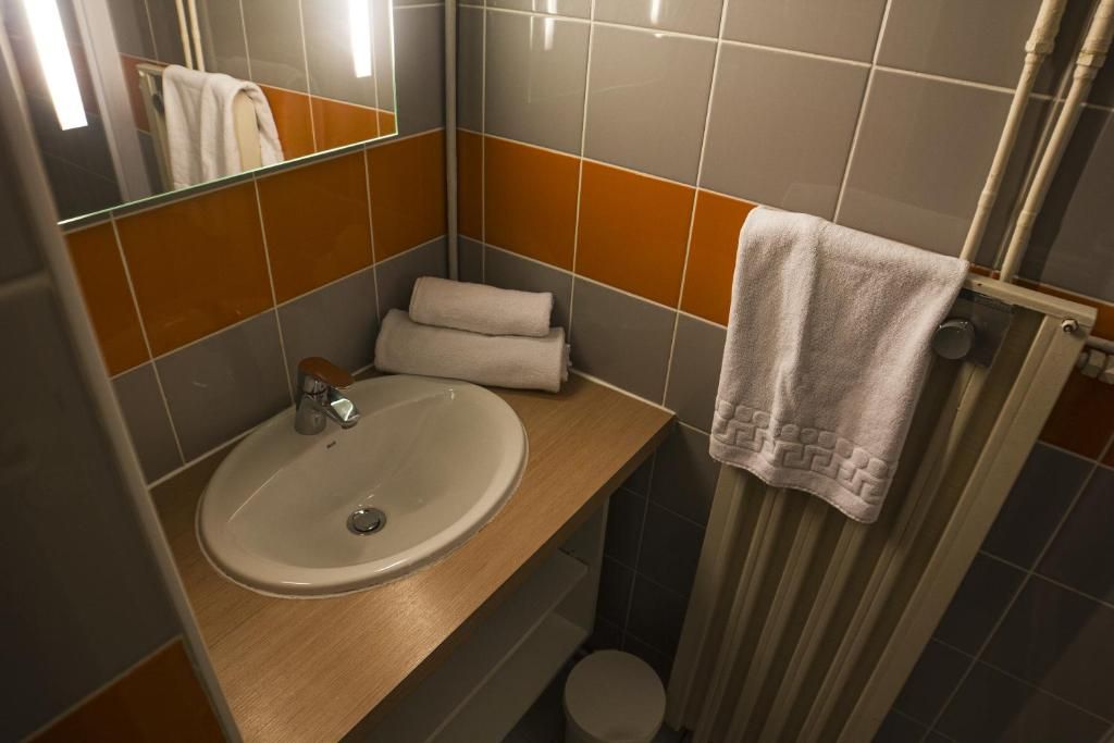 Une salle de bain équipée d’un lavabo, d’un miroir, d’un porte-serviettes et d’un rideau de douche.
