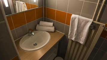 Une salle de bain équipée d’un lavabo, d’un miroir, d’un porte-serviettes et d’un rideau de douche.
