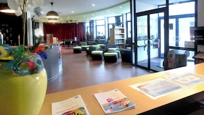 A modern lobby with a reception desk, seating area, and large windows.