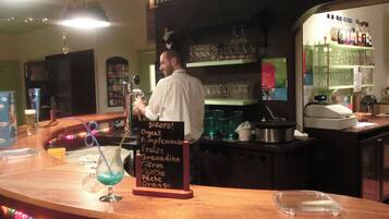 Eine Bar mit einem Barkeeper, einer Karte der angebotenen Getränke und Regalen mit Flaschen und Gläsern.