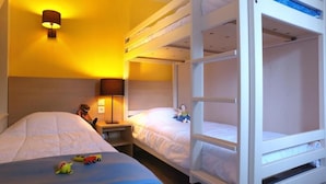 A room with bunk beds, a bedside table with a lamp, and a toy on the bed.