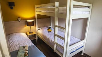 Une chambre avec un lit superposé, une table de chevet, une lampe et un jouet sur le lit du bas.