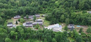 A cluster of buildings surrounded by dense forest, with multiple parking areas and a central building with a large roof. - Vvf Villages St Lary Soulan (Saint-Lary-Soulan)