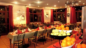 A restaurant with multiple tables set for dining, featuring a variety of fruits and a decorative centerpiece.