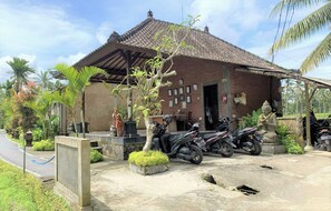 A traditional building with a tiled roof, a motorcycle parked in front, and a statue.