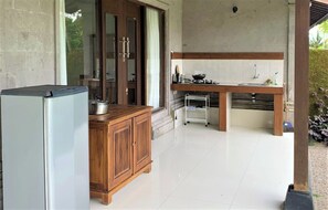 A kitchen with a refrigerator, wooden cabinets, a sink, and a stove.
