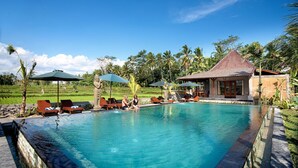 A swimming pool with lounge chairs, a small pavilion, and a lush garden in the background.