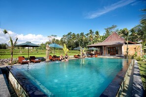 A swimming pool with lounge chairs, a small pavilion, and a lush garden in the background. - Bagiya Suites & Villas by Zuzu (Sebatu)