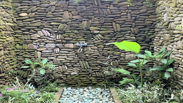 A stone wall with a water feature and plants.