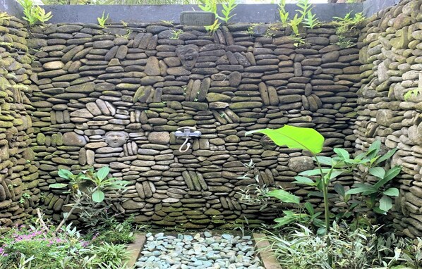 A stone wall with a water feature and plants. - Bagiya Suites & Villas by Zuzu (Sebatu)