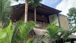 A building with a wooden balcony, surrounded by palm trees.