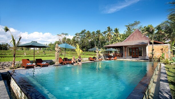 A swimming pool with lounge chairs, a small pavilion, and a lush garden in the background. - Bagiya Suites & Villas by Zuzu (Sebatu)