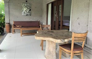A room with a stone table, wooden chairs, a bench, and a wall-mounted artwork. - Bagiya Suites & Villas by Zuzu (Sebatu)
