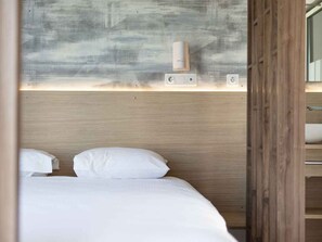 Ein Hotelzimmer mit einem Bett, einem an der Wand befestigten Luftreiniger und einem Holzschrank.