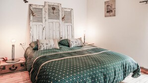 Een slaapkamer met een houten hoofdbord, beddengoed met een patroon en een nachtkastje met een lamp.
