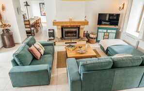 A living room with a fireplace, green sofas, a coffee table, and a TV. - Awesome home in Sevremont (Sevremont)
