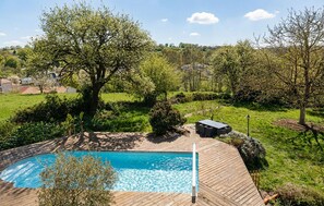 A swimming pool with a wooden deck, surrounded by greenery and trees. - Awesome home in Sevremont (Sevremont)