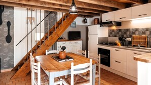 A kitchen with white cabinets, a wooden staircase, and a dining area with a wooden table and chairs. - Gorgeous home in Sevremont with WiFi (Sevremont)